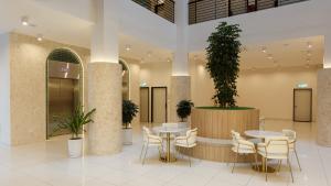un hall avec des tables et des chaises et une plante en pot dans l'établissement Wellesley Hotel, à Simpang Ampat