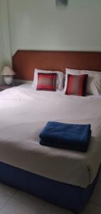 a large white bed with a blue pillow on it at Kingfisher House and Bar in Pattaya South