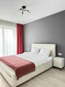 um quarto com uma cama branca e um cobertor vermelho em Room44 - Apartment em Brasov