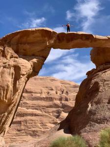 a man standing on top of a rock with a surfboard at Desert Nights Camp in Wadi Rum