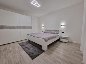 a white bedroom with a bed and a rug at House Palijan in Rakovica