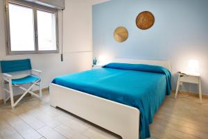 a white bedroom with a blue bed and a chair at siciliacasevancaze - Villa Torre in Punta Secca