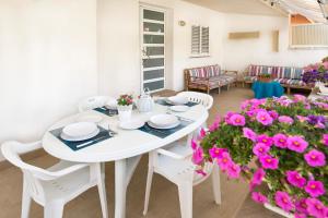 a white table and chairs in a living room with pink flowers at siciliacasevancaze - Villa Torre in Punta Secca