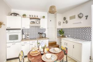 cocina con armarios blancos y mesa de madera en Gîte L'Escale - Maison de charme, en Chambellay