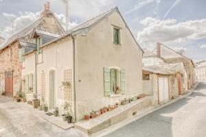 una casa blanca con persianas verdes en una calle en Gîte L'Escale - Maison de charme, en Chambellay