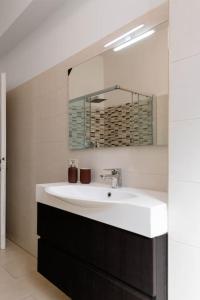 ein Badezimmer mit einem weißen Waschbecken und einem Spiegel in der Unterkunft Spazioso appartamento vicino EUR in Rom