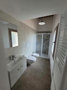 a white bathroom with a toilet and a sink at Ca’ Marinella in Combai