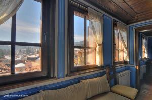 a room with a couch in front of some windows at Gozbarov's Guest House in Koprivshtitsa