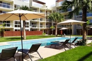 a pool with chairs and umbrellas next to a building at Casa Larimar 214 - Vibe Residence in La Laguna