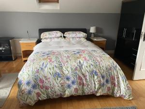 a bedroom with a large bed with a floral bedspread at Kilkenny rental The Folly Lodge minutes from city centre R95RYC8 in Kilkenny