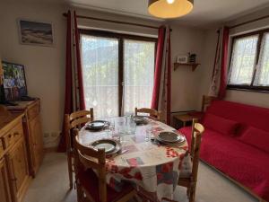 a room with a table and a red couch at Appartement Praz-sur-Arly, 2 pièces, 4 personnes - FR-1-603-39 in Praz-sur-Arly