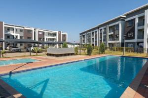 a swimming pool in front of some apartment buildings at One More Night Apartment E203 in Gaborone