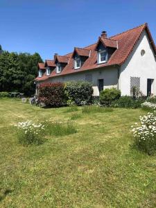 ein großes weißes Haus mit einem Hof mit Blumen in der Unterkunft La longère en Baie - au calme sur Saint Valery pour 4 in Saint-Valery-sur-Somme