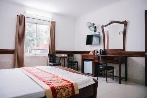 a bedroom with a bed and a desk and a mirror at HUNG HUONG HOTEL in Ho Chi Minh City