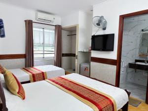 a hotel room with two beds and a television at HUNG HUONG HOTEL in Ho Chi Minh City
