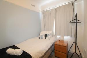 ein weißes Schlafzimmer mit einem Bett und einem Fenster in der Unterkunft Upton Hidden Garden Retreat in Birkenhead