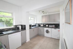 eine Küche mit weißen Schränken, einer Waschmaschine und einem Trockner in der Unterkunft Upton Hidden Garden Retreat in Birkenhead