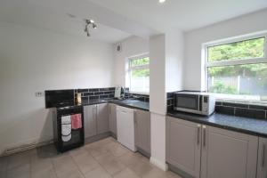 a kitchen with a sink and a microwave at Upton Hidden Garden Retreat in Birkenhead