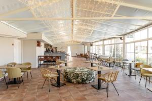 een eetkamer met tafels, stoelen en ramen bij Makkan Club in Oleiros