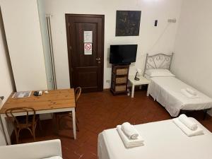 een kleine kamer met een bed, een tafel en een tv bij Sosta Paradisa in Pisa