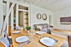 a dining room with a table and chairs and a couch at Superbe Appartement Bon marché Saint Germain Free Netflix in Paris