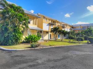 a large yellow building with palm trees and a street at Grand appartement confortable 2 chambres proche marina in Saint-François