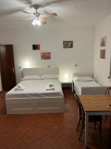 een slaapkamer met 2 bedden, een tafel en een plafondventilator bij Sosta Paradisa in Pisa
