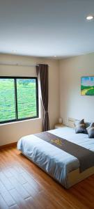 um quarto com 2 camas e uma grande janela em Đồi Chè Hotel em Mộc Châu