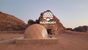 una tenda in mezzo al deserto con un cartello di Harmony Luxury Camp a Wadi Rum