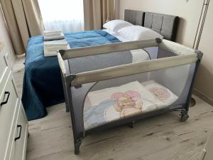 a baby crib in a bedroom next to a bed at Apartament BARI in Świnoujście
