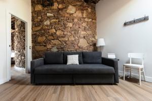 - un canapé dans le salon avec un mur en pierre dans l'établissement 31 steps to Heaven - Heart of Lucca, à Lucques