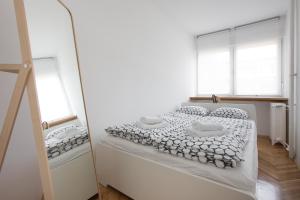 a white bedroom with a bed and two windows at Miramare in Zagreb