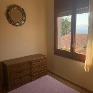 een slaapkamer met een dressoir, een spiegel en een raam bij Costa Brava Home in Terra Brava
