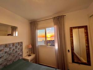 1 dormitorio con cama, ventana y espejo en Beachfront Penthouse Apartment with Large Terrace and Breathtaking Sea Views close to Marbella Spain, en Mijas Costa