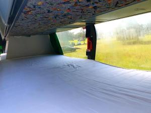 een bed achterin een camper met een raam bij Kapsuły Sypialne AutokarSingliPL, Par, ciekawe miejsce in Władysławowo