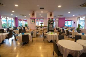 uma sala de jantar com mesas e cadeiras brancas em Hotel Corallo em Pietra Ligure