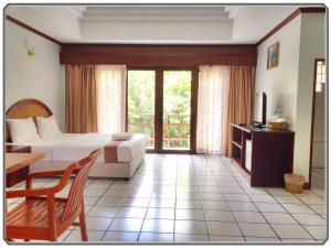 1 dormitorio con cama, mesa y TV en Thong Paeka Hotel, en Prasat