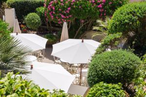 um grupo de guarda-sóis brancos e cadeiras com flores em Hôtel La Caravelle em Calvi