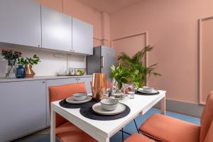 a kitchen with a white table and orange chairs at Hostel Krasnal Market Square Wroclaw in Wrocław