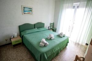 um quarto com uma cama verde e toalhas em Hotel Corallo em Pietra Ligure