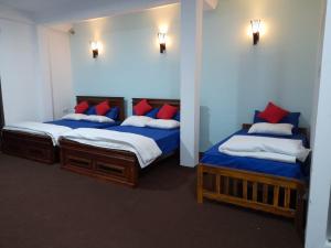 two beds in a room with blue and red pillows at Kithaya Ella in Ella