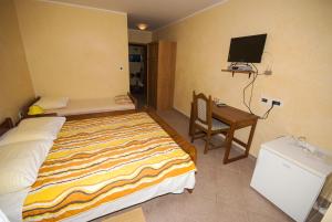 a bedroom with a bed and a desk and a television at Guesthouse Villa Lena in Premantura
