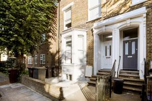a white front door of a brick house at Luxury Hackney Apartment 10 mins to Liverpool Street in London
