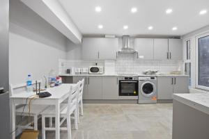 a kitchen with white appliances and a table and chairs at Luxury Hackney Apartment 10 mins to Liverpool Street in London