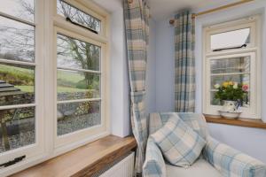 een woonkamer met ramen en een stoel bij 2 Lower Spire in Dulverton