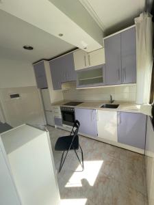 una cocina con armarios blancos y una silla. en Como en casa, en Barakaldo