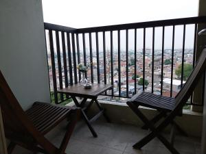 - un balcon avec deux chaises et une table avec vue dans l'établissement The Wave Apartment, à Jakarta