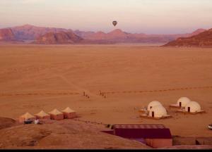 una mongolfiera che vola sopra un deserto con tende di Aljawhara camp and activities a Wadi Rum