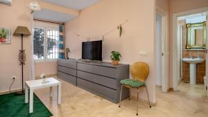 - un salon avec une commode, une télévision et une chaise dans l'établissement Sunlit Retreat with Garden Haven, à Fuengirola
