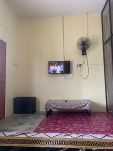 a room with a tv on the wall with a bench at Tina Homestay Budget in Ketereh